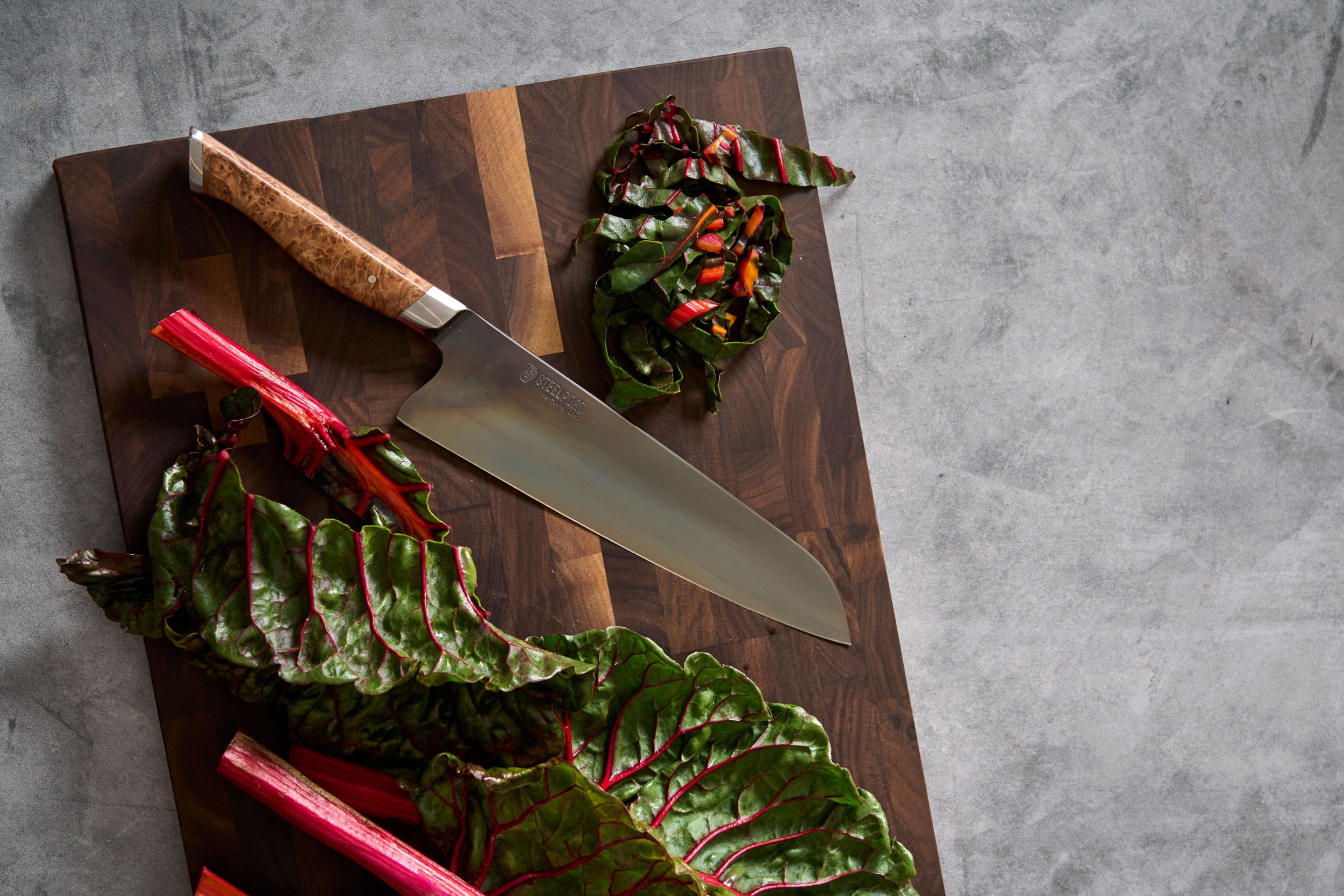 Chopped Swiss chard on a SteelCore™ cutting board with a STEELPORT knife on a gray surface