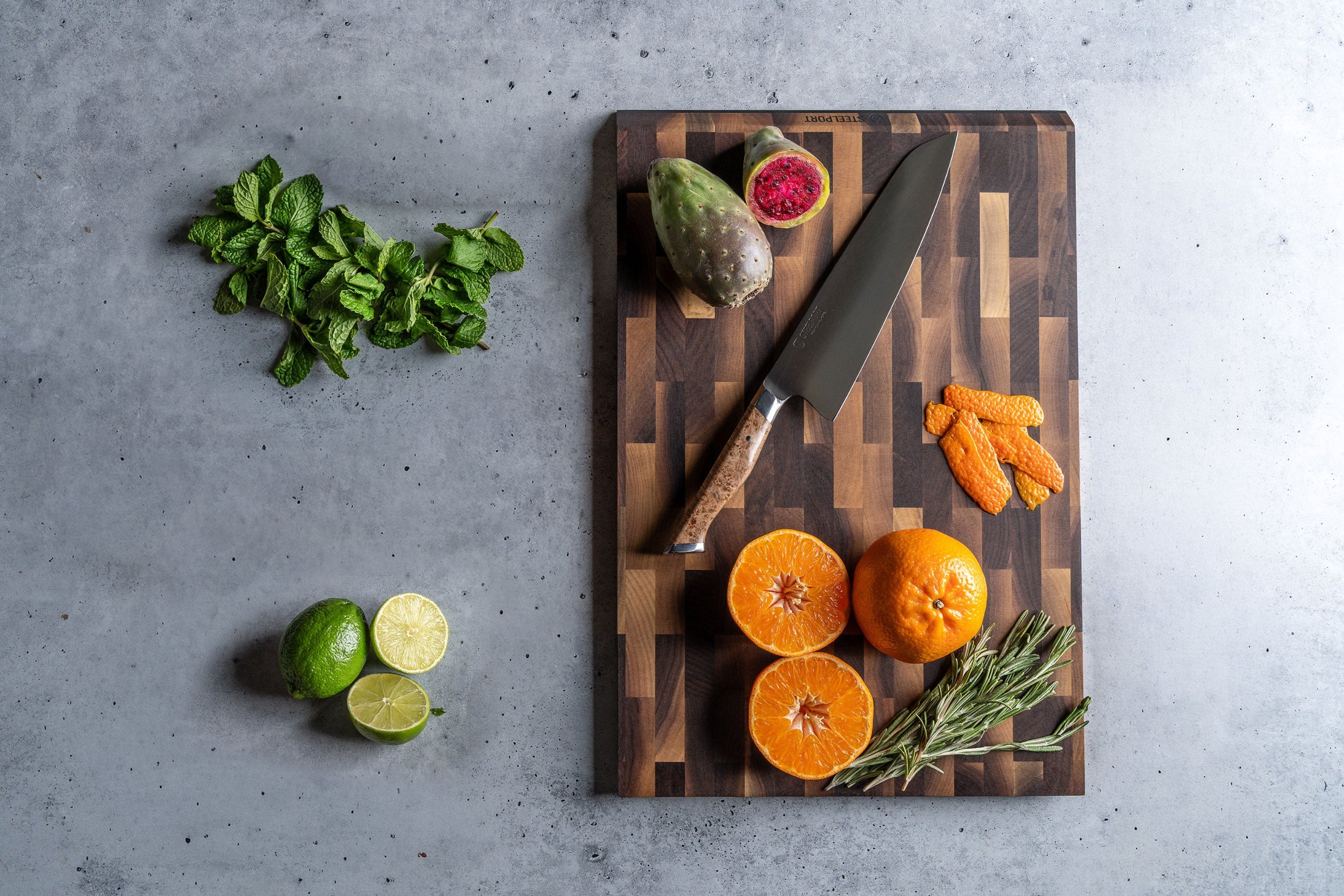 SteelCore™ cutting board with fruits, vegetables, and STEELPORT knife on a gray surface