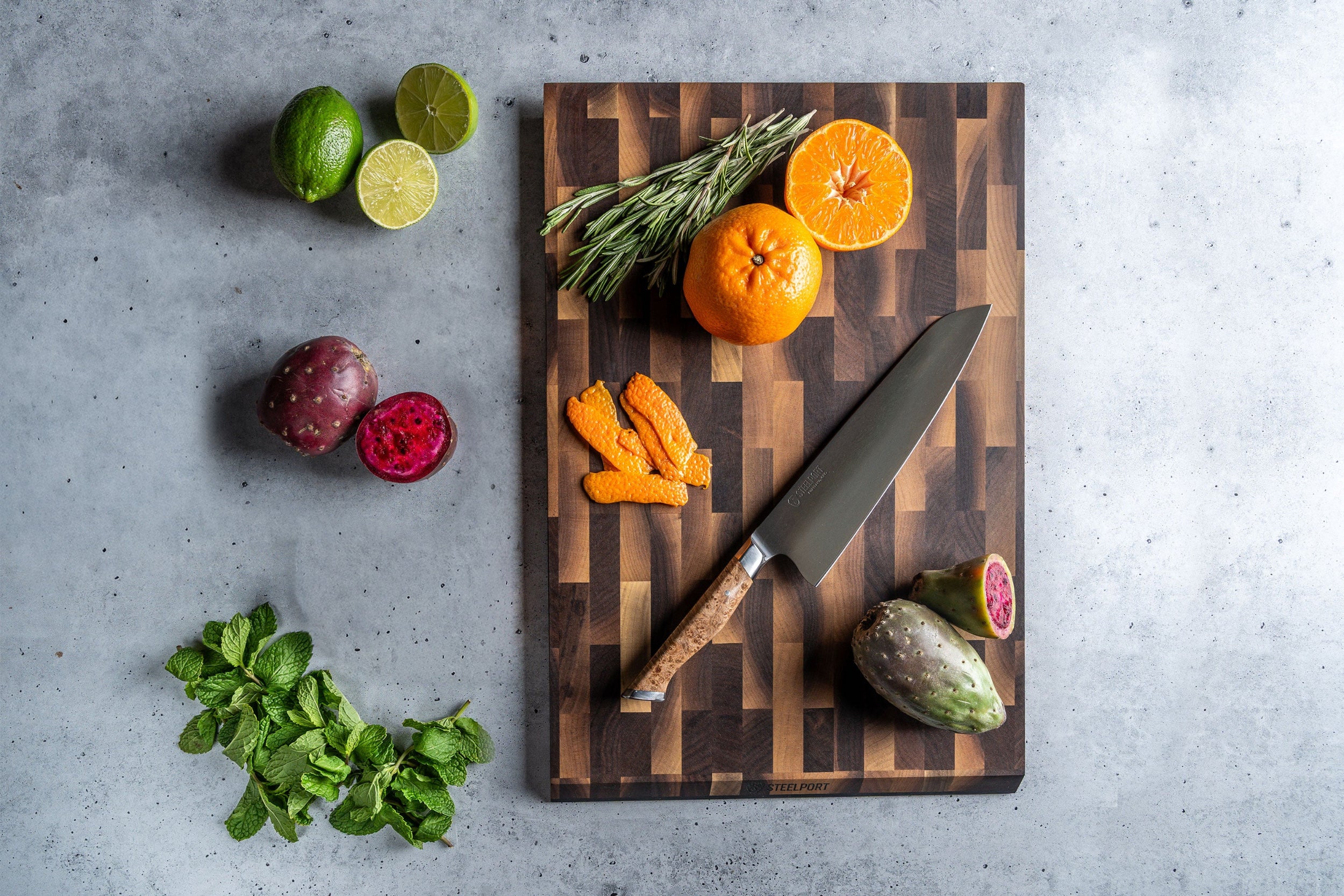 SteelCore™ cutting board with fruits, vegetables, and STEELPORT 8" Chef Knife on a gray surface
