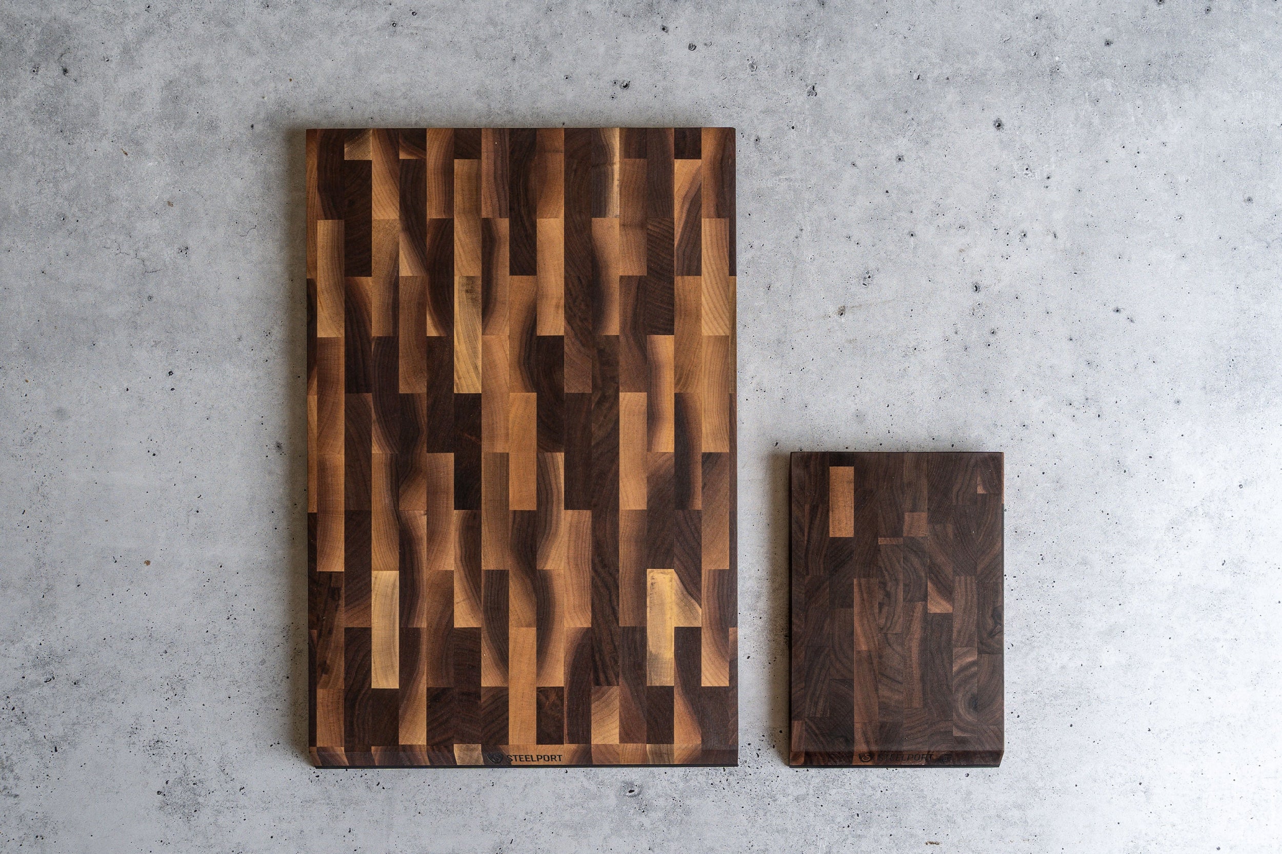 Two SteelCore™ cutting boards with a geometric pattern on a gray concrete surface